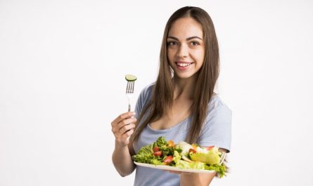 kobieta trzyma widelec i talerz z zdrowymi warzywami